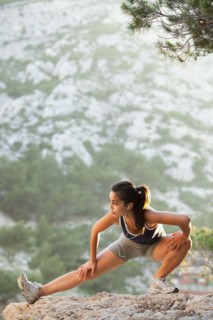 France, Marseille, Young woman stretching on cliff. Photo : Mike Kemp