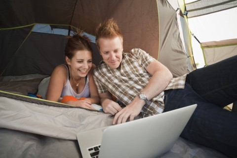 Hikers in tent using laptop. Photo : Mike Kemp