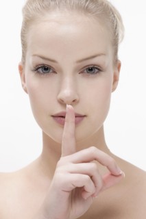 Young woman pressing finger against mouth. Photo : Jan Scherders