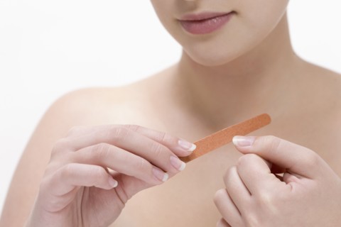 Beauty shot of woman using nail file. Photo : Jan Scherders