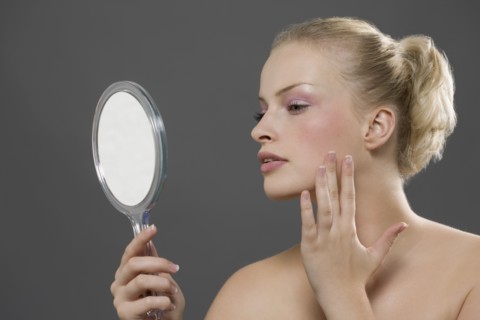 Beauty portrait of woman looking in mirror. Photo: Jan Scherders