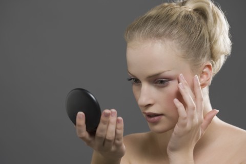 Beauty portrait of woman using powder compact. Photo : Jan Scherders