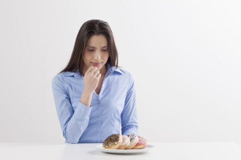 Studio shot of woman looking at donuts. Photo: Jan Scherders