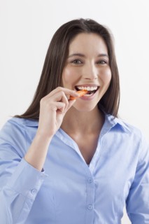 Studio shot of woman eating baby carrots. Photo : Jan Scherders