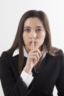 Young woman with finger on her lips, studio shot. Photo : Jan Scherders