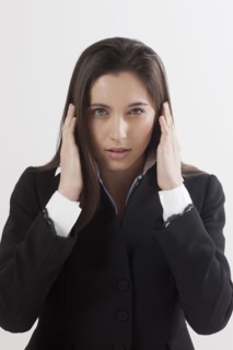 Portrait of young woman with hands covering ears, studio shot. Photo : Jan Scherders