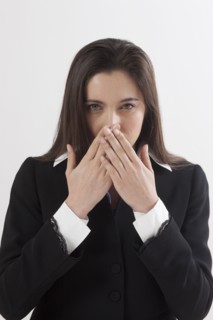 Portrait of young woman with hands covering lips, studio shot. Photo : Jan Scherders