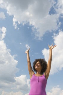 Woman stretching under blue sky.