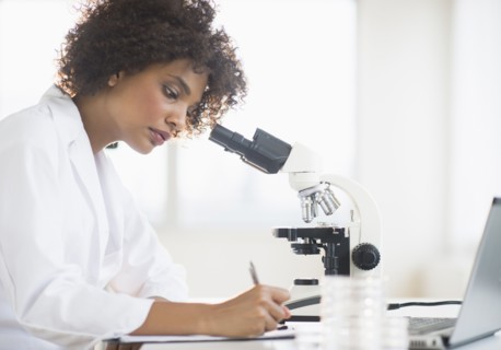 Woman using microscope in laboratory.