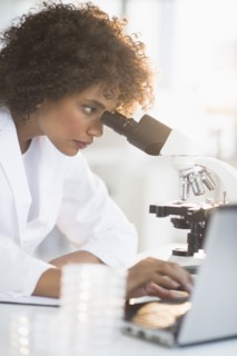 Woman using microscope in laboratory.