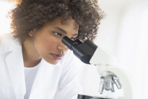 Woman using microscope in laboratory.