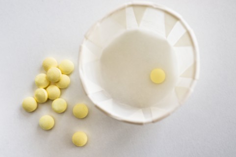 Yellow pills with cup, studio shot.