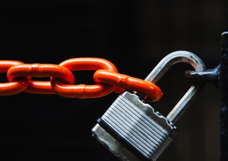 Chain with padlock on black background, studio shot.