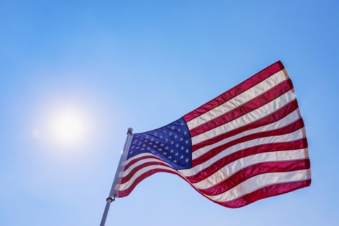 US flag against blue sky.