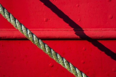 Detail of red tugboat with rope.