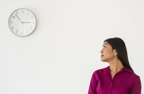 Woman looking at clock on wall.