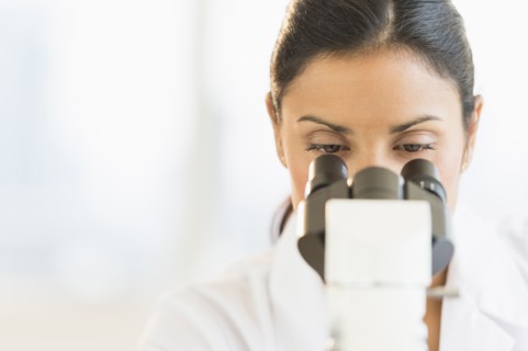 Female scientist looking through microscope.