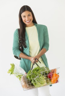 Studio shot of woman holding shopping basket with vegetables.