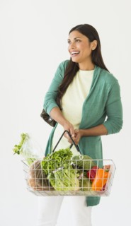 Studio shot of woman holding shopping basket with vegetables.