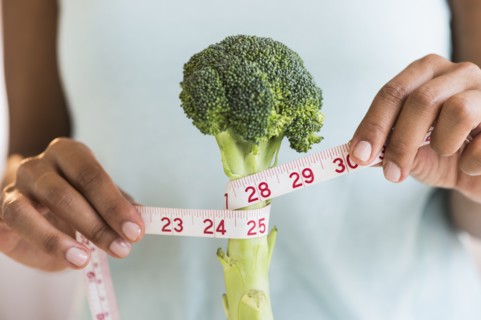 Woman measuring broccoli .