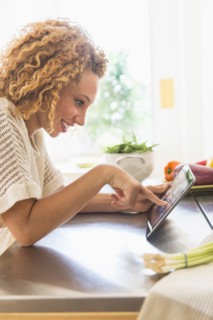 Young woman using digital tablet in kitchen.