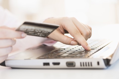 Close up of woman's hand doing online banking with laptop.