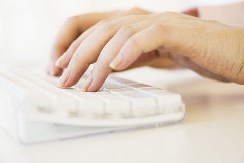 Close up of woman's hands typing on computer keyboard .