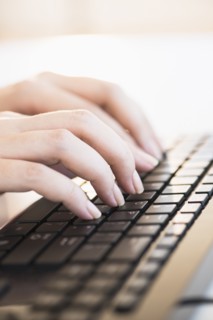 Close up of woman's hands typing on computer keyboard .