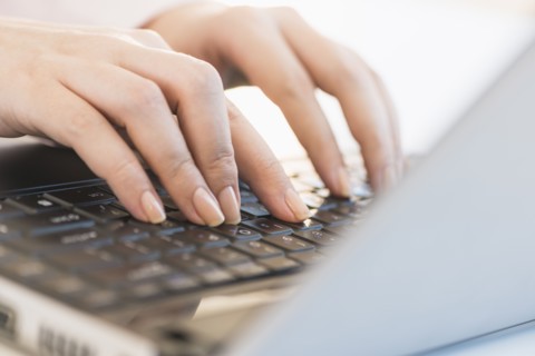 Close up of woman's hands typing on computer keyboard .