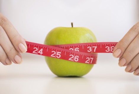 Woman measuring green apple.
