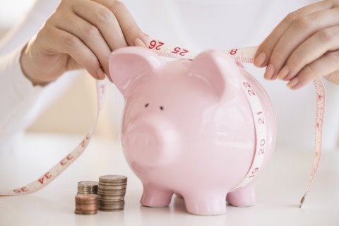 Woman measuring piggybank.
