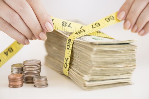 Woman measuring bunch of banknotes.