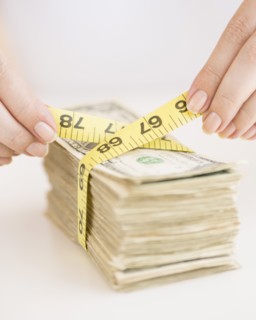Woman measuring bunch of banknotes.