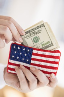 Woman holding banknotes and purse with american flag on it.
