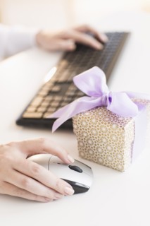 Gift box on desk next to woman using computer.
