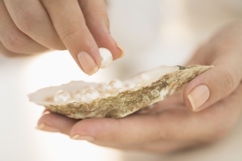 Woman holding shell and pearl.