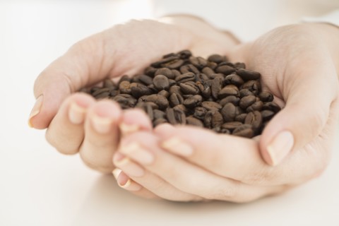 Coffee beans on woman's hand.
