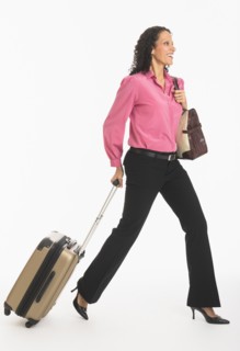 Studio shot of woman walking with suitcase.