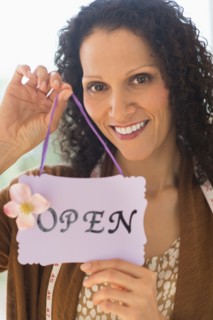 Portrait of woman holding open sign.
