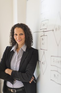 Portrait of woman standing next to whiteboard.