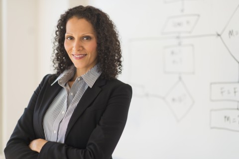 Portrait of woman standing next to whiteboard.