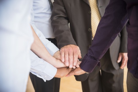 Office workers holding hands. Photo : Jamie Grill