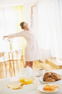 Breakfast scene with woman in white robe stretching. Photo : Daniel Grill