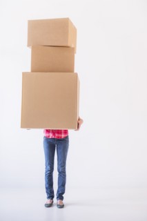 Studio shot of young woman carrying stack of boxes. Photo: Daniel Grill