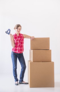 Studio shot of young woman with tape and stack of boxes. Photo: Daniel Grill