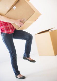 Studio shot of young woman carrying stack of boxes, low section. Photo: Daniel Grill