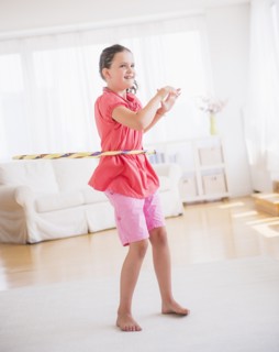 Young girl (8-9) playing with hula hoop. Photo : Daniel Grill