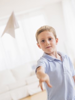 Young boy (6-7) playing with paper plane. Photo : Daniel Grill