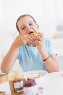 Happy young girl (8-9) having breakfast. Photo : Daniel Grill