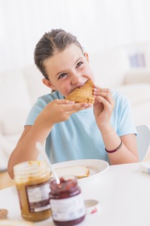 Happy young girl (8-9) having breakfast. Photo : Daniel Grill